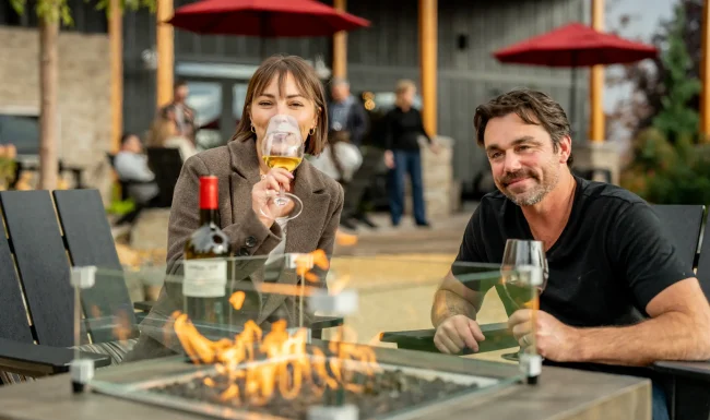 Couple enjoying a bottle of Whitman Hill wine by the fire