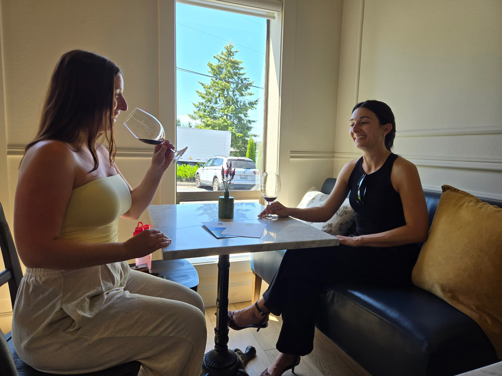Two women enjoying wine at a table inside